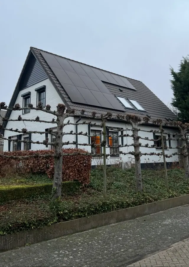 Witte vrijstaande woning met zwarte zonnepanelen op het dak
